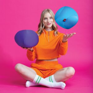 Lifestyle shot of woman juggling purple and blue Dohzee balls while sitting