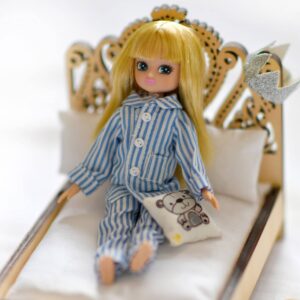 Pajama Party Lifestyle Shot - Lottie doll wearing striped pajamas on a small bed