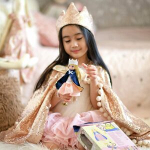 Girl in a queen costume holding Queen Of The Castle Lottie next to opened package