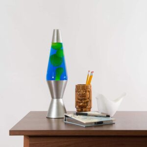 14.5” LAVA® Lamp – Yellow/Blue/Silver on a table with a notebook and tiki mug pencil cup