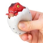 Squeezy Egg Popper toy in hand, squeezed and dino popping out
