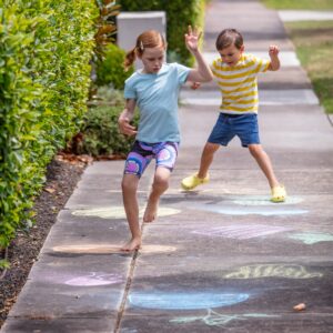 Tiger Tribe Chalk It Up - Lifestyle shot of a girl and boy jumping on chalk drawings on the sidewalk