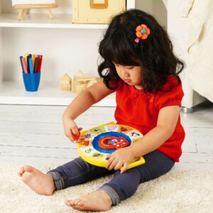 Lifestyle shot of girl sitting on a bedroom floor playing with the Fisher-Price See N Say