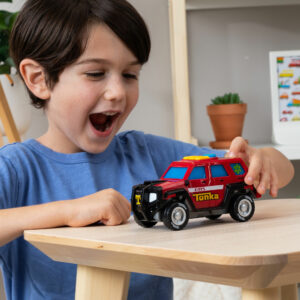 Tonka Mighty Force - First Responder - Lifestyle shot of excited boy paying with vehicle on a table