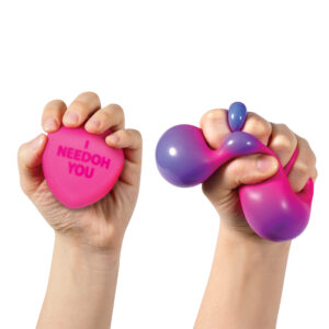 Two hands squeezing colorful sensory hearts. The left hand holds a pink heart-shaped sensory toy with the words "I NEEDOH YOU" printed on it. The right hand is squeezing a fluid, malleable sensory toy that transitions from pink to purple.