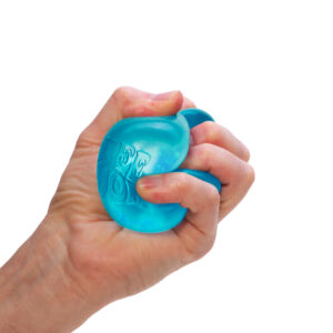 A hand is squeezing a blue sensory toy against a white background. The NeeDoh toy has some texture and appears slightly translucent. The fingers are wrapped tightly around it, indicating a firm grip.