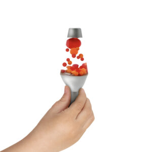 A hand holding a small, squishy silver Lava Lamp toy. Red and orange globs float upward from the base, giving the illusion of the lamp's typical flowing motion against a plain white background.