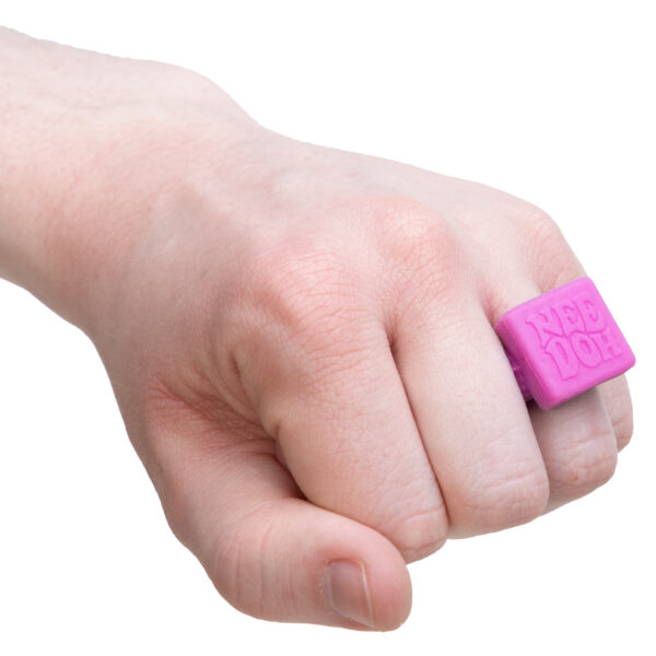 A hand on a white background wearing a pink squishy ring on the ring finger that says NeeDoh.