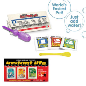 Three packets, numbered 1, 2, and 3 from left to right. There is a small yellow Sea-Monkeys spoon laying in front of the packets. There is a purple pipette and folded instruction paper laying behind the packets, and a peice of the box highlighted in front of the packets. There are two callouts in circles. One reads "World's Easiest Pet!" and the other reads "Just add water!" Three packets, numbered 1, 2, and 3 from left to right. There is a small yellow Sea-Monkeys spoon laying in front of the packets. There is a purple pipette and folded instruction paper laying behind the packets, and a peice of the box highlighted in front of the packets. There are two callouts in circles. One reads "World's Easiest Pet!" and the other reads "Just add water!"